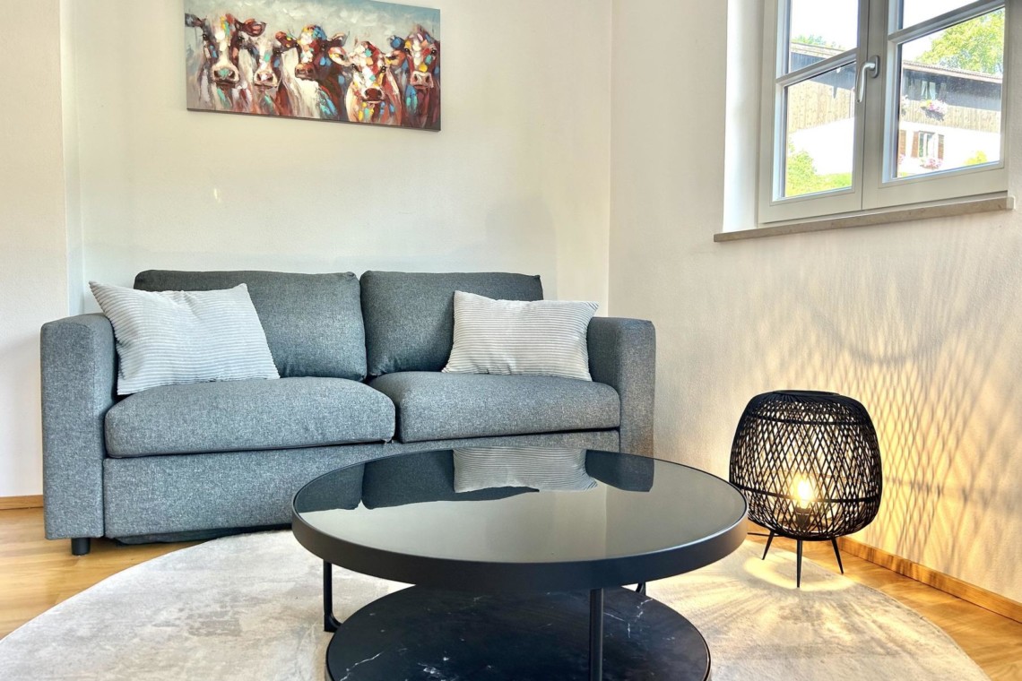 Helles, modernes Wohnzimmer in Hausham mit bequemer Couch, Kunst an der Wand und stilvollem Tisch.