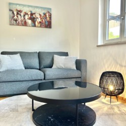 Helles, modernes Wohnzimmer in Hausham mit bequemer Couch, Kunst an der Wand und stilvollem Tisch.
