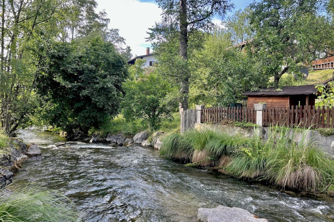 Idyllische Ferienwohnung "Huberspitz" in Hausham mit Blick auf einen Bach, umgeben von Grün, optimal für Erholung und Naturgenuss.