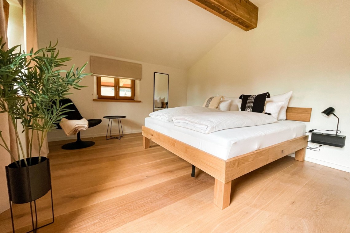 Helles Schlafzimmer in Kreuther Ferienwohnung mit Holzboden und stilvoller Einrichtung.