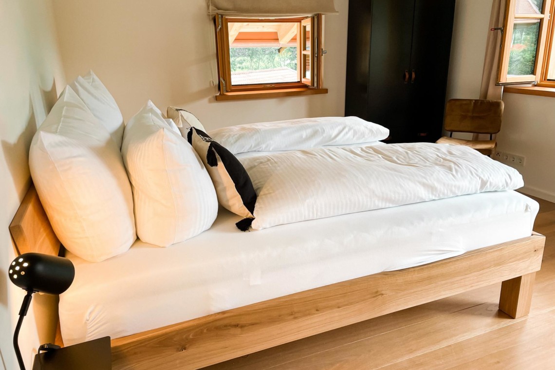 Helles Zimmer in Kreuth Ferienhaus mit gemütlichem Doppelbett und modernem Interieur. Ideal für Entspannung und Urlaub.