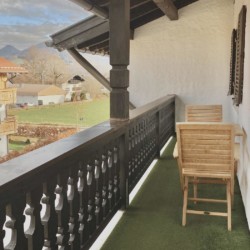Charmantes Balkonbild einer Ferienwohnung in Bad Wiessee mit Bergblick und traditioneller Architektur. Ideal für entspannte Tage am Tegernsee.