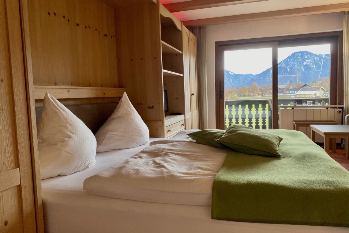 Gemütliches Schlafzimmer mit Bergblick in einer Ferienwohnung am Tegernsee, ideal für den Urlaub in Bad Wiessee.