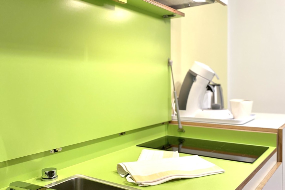 Moderne Küchenzeile in Ferienwohnung Bad Wiessee mit leuchtender Rückwand für gemütliche Selbstversorgung.