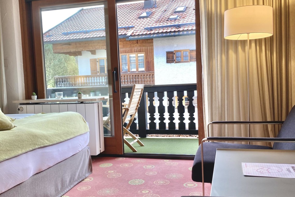 Gemütliches Zimmer in Bad Wiessee mit Balkonblick auf Alpen, ideal für Tegernsee-Urlaub.