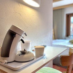 Gemütliches Zimmer in Bad Wiessee: Tisch mit Kaffeemaschine, einladende Beleuchtung und warme Farben. Ideal für den Tegernsee-Urlaub.