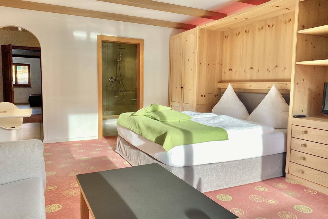 Gemütliches Zimmer in Bad Wiessee mit Bett, Holzmöbeln und Dusche. Ideal für den Urlaub am Tegernsee.
