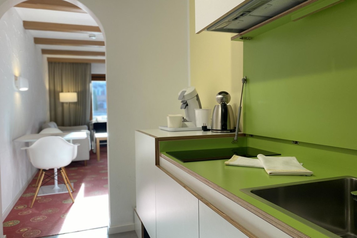 Helles, modernes Apartment in Bad Wiessee mit grüner Küche, komfortablem Wohnbereich und elegantem Design. Ideal für Ihren Urlaub!