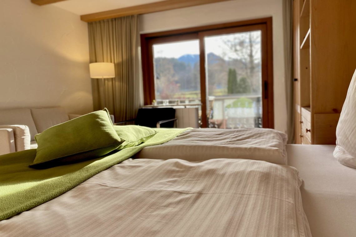Gemütliches Schlafzimmer in Ferienwohnung in Bad Wiessee mit Balkonblick auf Natur.