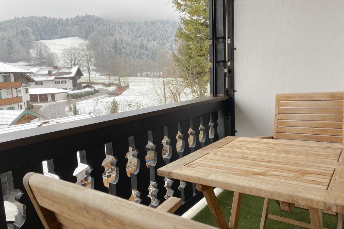 Gemütlicher Südwestbalkon mit Blick auf verschneite Hügel in Bad Wiessee. Ideal für Erholung.