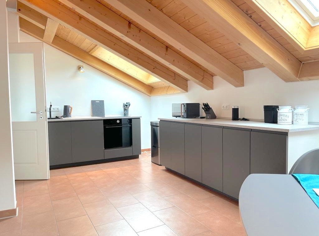 Gemütliche Penthouse-Küche in Bad Wiessee mit moderner Ausstattung und Holzbalken, ideal für Urlaub am Tegernsee.