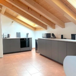 Gemütliche Penthouse-Küche in Bad Wiessee mit moderner Ausstattung und Holzbalken, ideal für Urlaub am Tegernsee.