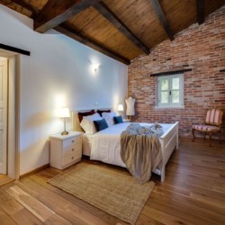 Gemütliches Zimmer in Villa Avalon, Muntrij, mit Holzbalken, Backsteinwand und eleganter Einrichtung – ideal für Ihren Urlaub.