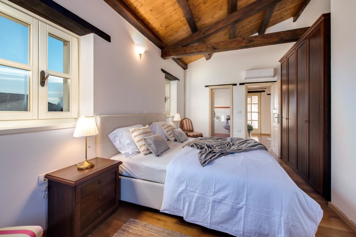 Gemütliches Schlafzimmer in Villa Avalon, Muntrij mit Holzbalken, rustikalem Charme und modernen Annehmlichkeiten. Ideal für Urlaub.