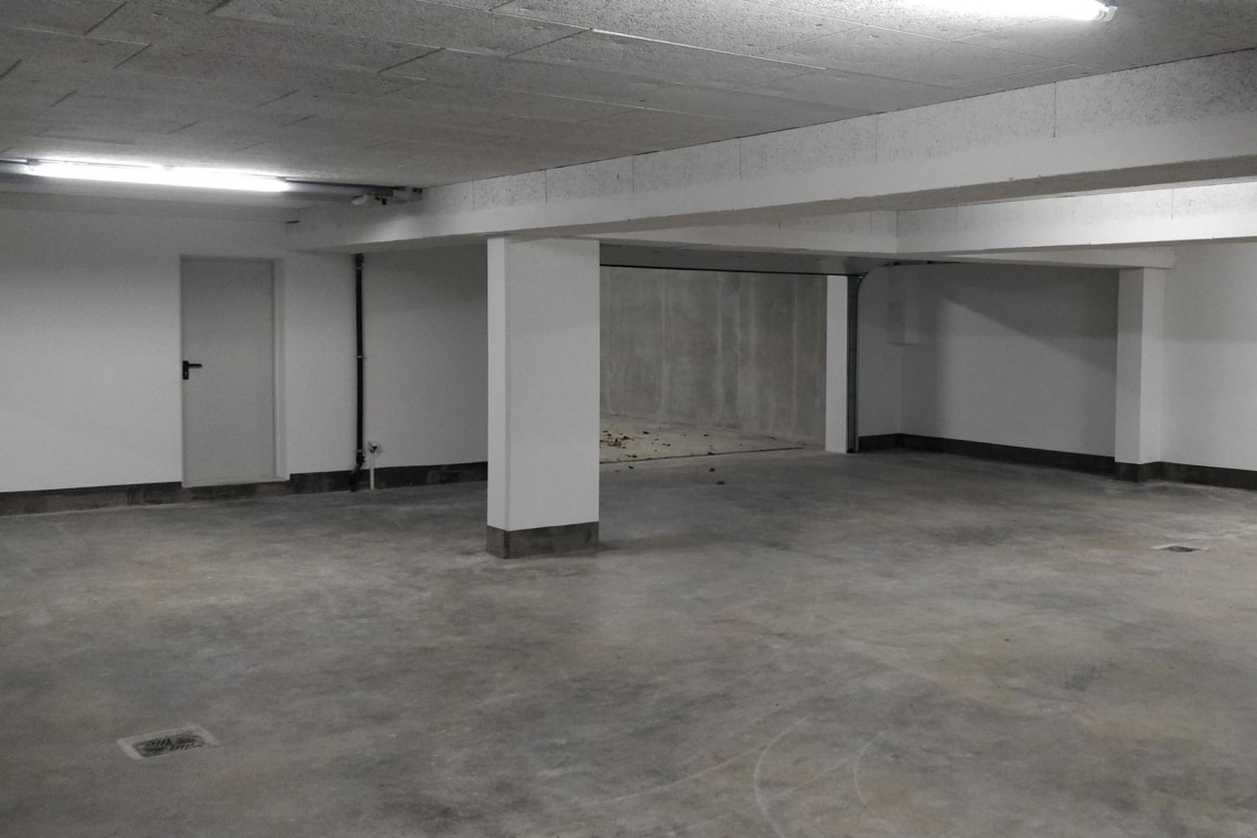 Leere Garage mit Betonboden und Säulen, nicht repräsentativ für Ferienwohnung.