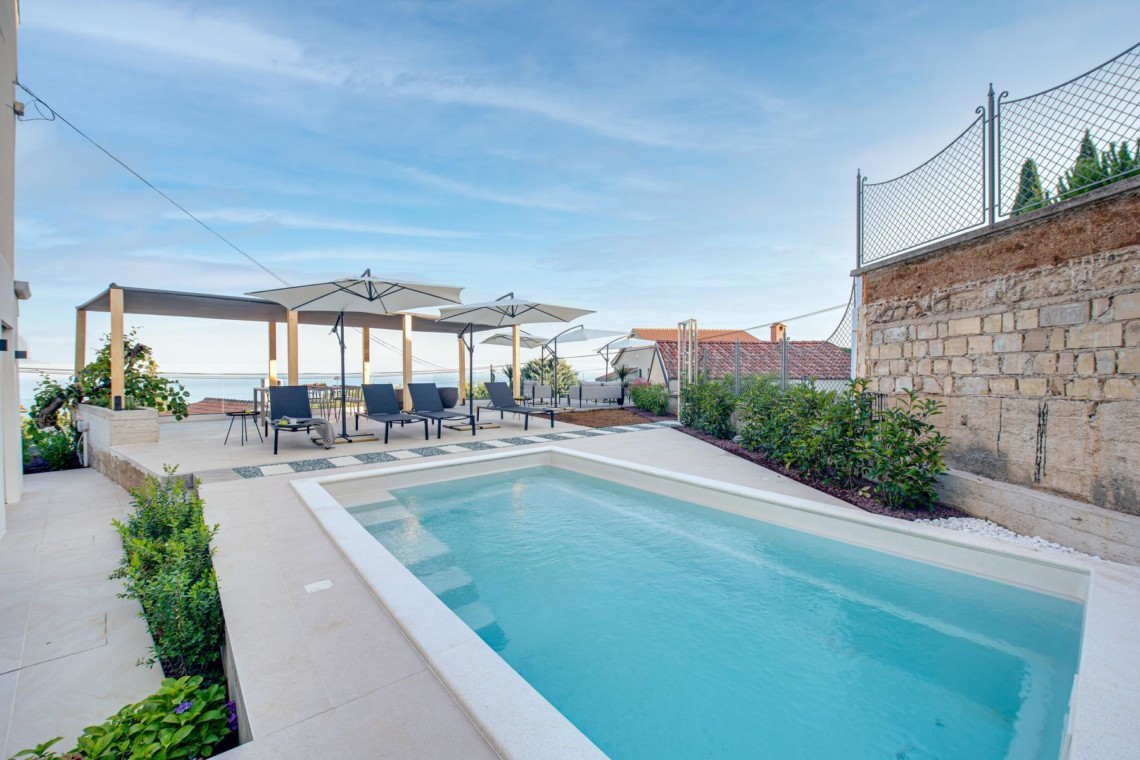 Luxuriöses Apartment in Opatija mit Pool, Sonnenschirmen & Liegestühlen, ideal für erholsamen Urlaub.