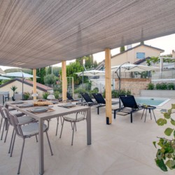 Gemütliche Terrasse in Opatija: Modernes Apartment mit Poolzugang, Sonnenliegen und schattigem Essbereich im Freien.