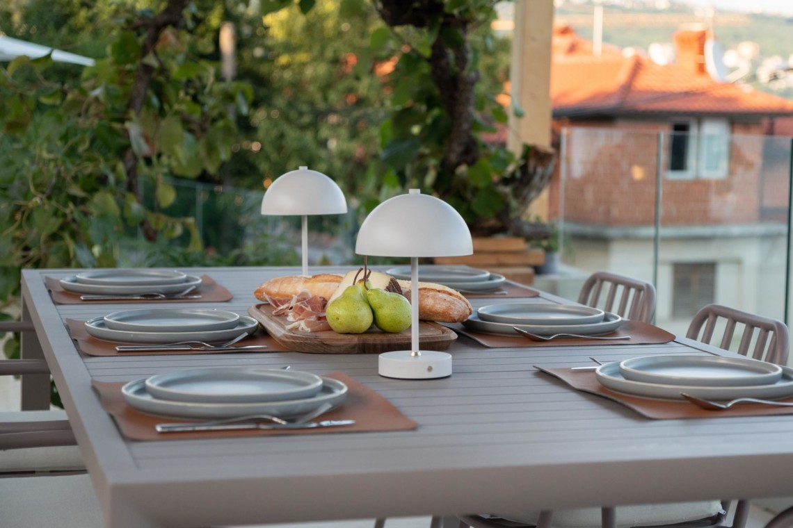 Gemütliches Essbereich auf Balkon in Opatija, ideal für Mahlzeiten im Freien mit Blick auf die Stadt.
