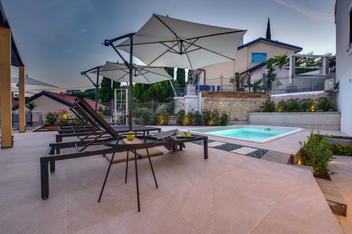 Entspannender Poolbereich mit Sonnenliegen und Schirmen in Opatija. Ideal für einen komfortablen Urlaub.