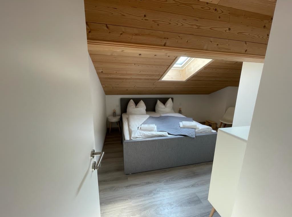 Gemütliches Dachgeschoss-Schlafzimmer in Bad Wiessee Ferienwohnung mit Holzdecke und modernem Design. Perfect for relaxing stays.