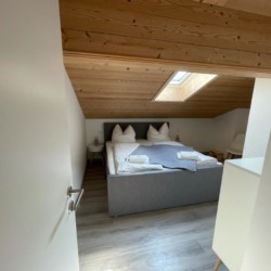 Gemütliches Dachgeschoss-Schlafzimmer in Bad Wiessee Ferienwohnung mit Holzdecke und modernem Design. Perfect for relaxing stays.