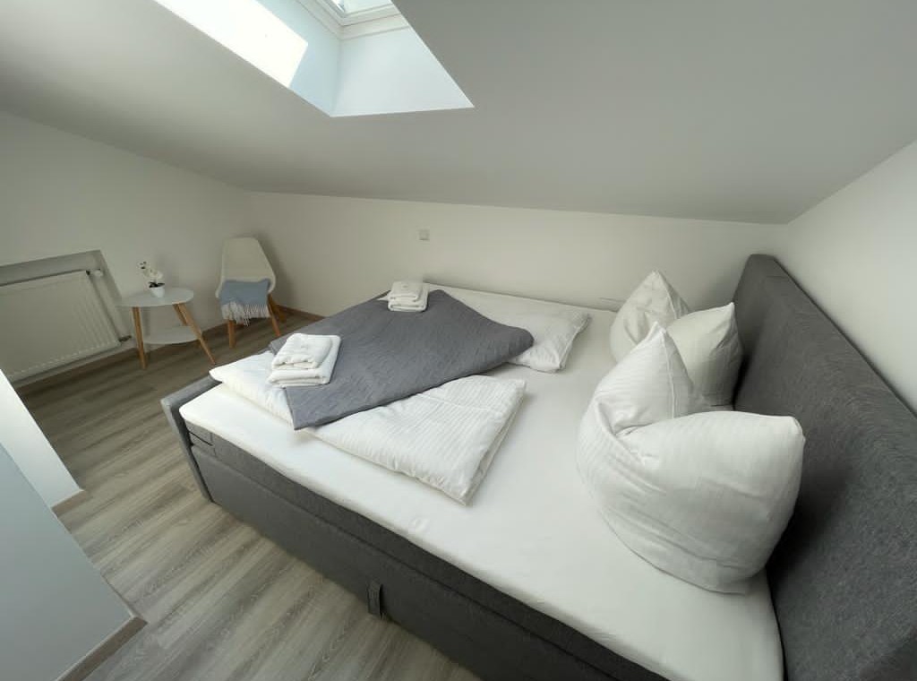 Gemütliches Schlafzimmer in Bad Wiesseer Ferienwohnung mit Dachschräge und moderner Einrichtung.