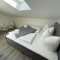 Gemütliches Schlafzimmer in Bad Wiesseer Ferienwohnung mit Dachschräge und moderner Einrichtung.