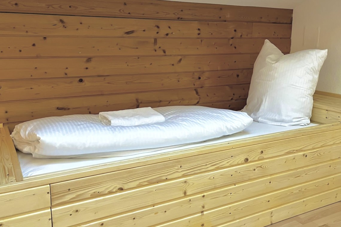 Gemütliches Bett in einer hellen Ferienwohnung in Bayrischzell, ideal für Entspannung nach Wandertouren.