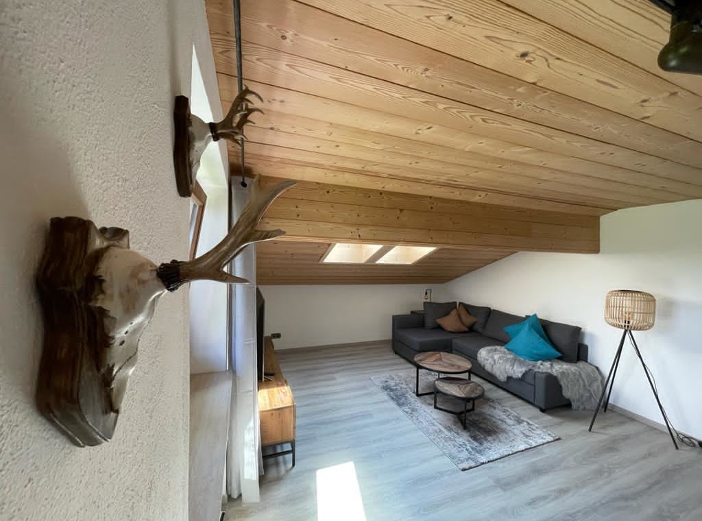 Helle, stilvolle Ferienwohnung in Bad Wiessee mit gemütlichem Sofa und modernem Holzinterieur.