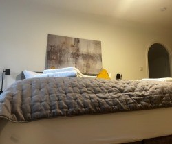Gemütliches Schlafzimmer mit Kunst in einer Ferienwohnung in Rottach-Egern. Ideal für Entspannung & als Arbeitsort.