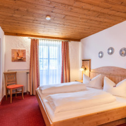 Gemütliches Schlafzimmer in einer Schlierseer Ferienwohnung mit Holzdecke, komfortablem Bett und gemütlichem Ambiente.