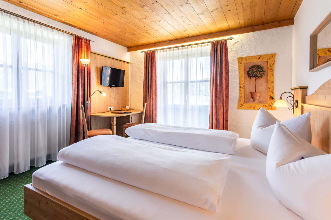 Gemütliches Zimmer in Schliersee mit Holzdecke, bequemen Betten und charmantem Dekor.