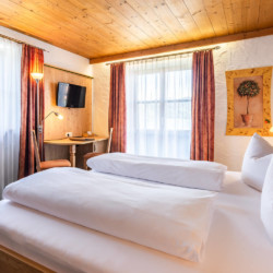 Gemütliches Zimmer in Schliersee mit Holzdecke, bequemen Betten und charmantem Dekor.