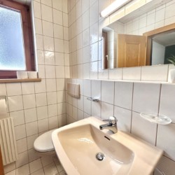 Helles, sauberes Badezimmer mit Spiegel und Fenster in Warther Unterkunft.