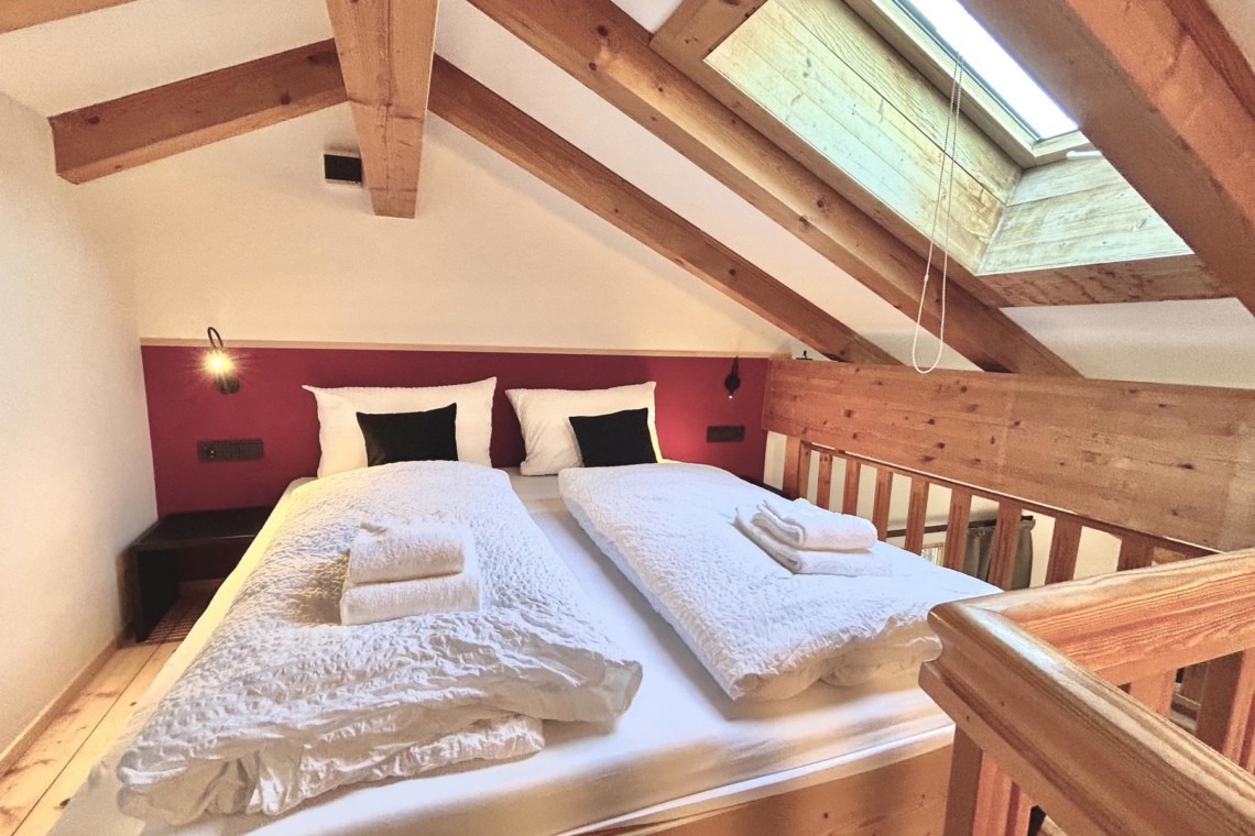 Gemütliches Dachzimmer in Bad Wiessee mit bequemen Betten und ansprechendem Holzinterieur.