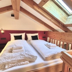 Gemütliches Dachzimmer in Bad Wiessee mit bequemen Betten und ansprechendem Holzinterieur.