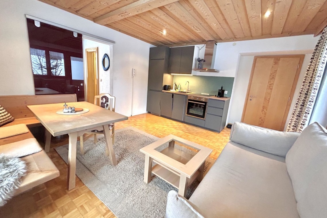 Gemütliches, helles Wohnzimmer mit Küche in einer Ferienwohnung in Warth am Arlberg. Ideal für Urlaub in den Alpen.