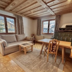 Gemütliches Ferienhaus in Warth am Arlberg mit Kachelofen, bequemem Sofa und traditionellem Dekor. Ideal für einen Bergurlaub.