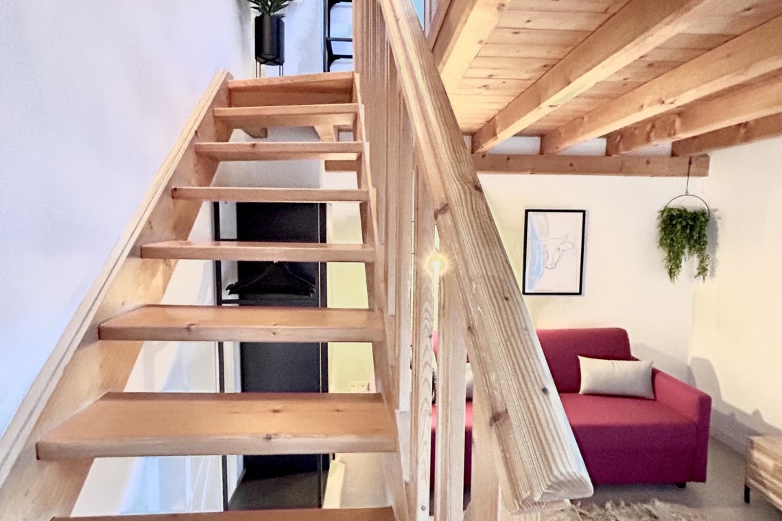 Gemütliche Dachwohnung mit Holztreppe und einladendem Interieur in Bad Wiessee am See. Ideal für Urlaub und Erholung. #Ferienwohnung