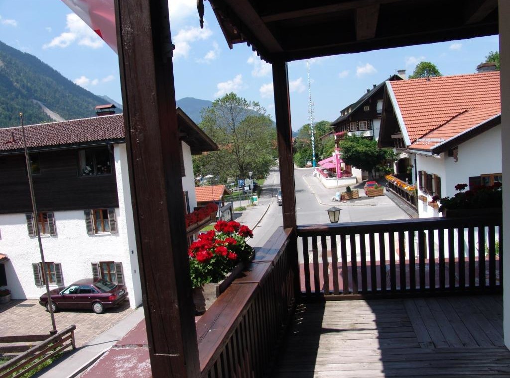 Gemütlicher Balkon mit Blumen und Blick auf Alpenstraße – ideal für Entspannung in der Ferienwohnung "Miesing".