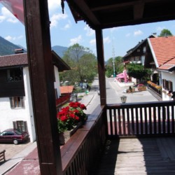 Gemütlicher Balkon mit Blumen und Blick auf Alpenstraße – ideal für Entspannung in der Ferienwohnung "Miesing".