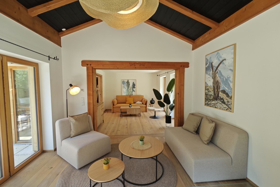 Gemütliches Ferienhaus-Interieur, offener Raum mit Holzbalken, stilvolle Einrichtung und viel Licht. Ideal für Erholung am Schliersee.