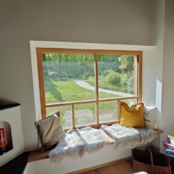 Gemütliches Fenstersitzplatz mit Blick ins Grüne bei Ferienhaus am Schliersee. Ideal für Erholung und Naturgenuss.