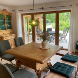 Gemütliches Ferienhaus-Ambiente mit Holztisch, Terrasse und grüner Aussicht – ideal für Erholung am Schliersee.