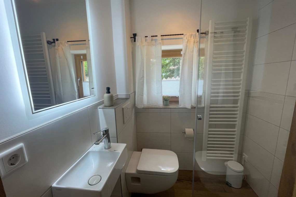 Helles, sauberes Badezimmer mit Dusche, ideal für einen entspannenden Aufenthalt am Schliersee.