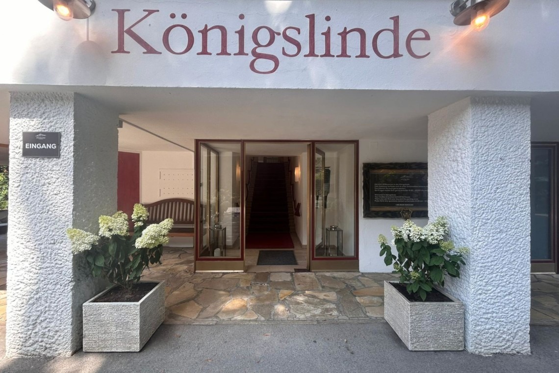 Eingangsbereich der "Königslinde" Ferienwohnung in Thiersee mit Pflanzen und Schild, einladende und ruhige Atmosphäre.