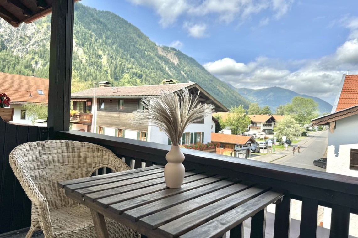 Gemütlicher Balkon mit Blick auf Berge und Dorf, ideal für eine entspannende Auszeit in der Natur.