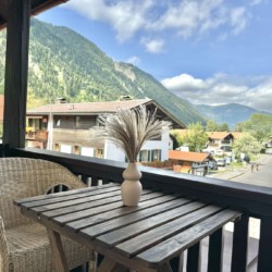 Gemütlicher Balkon mit Blick auf Berge und Dorf, ideal für eine entspannende Auszeit in der Natur.