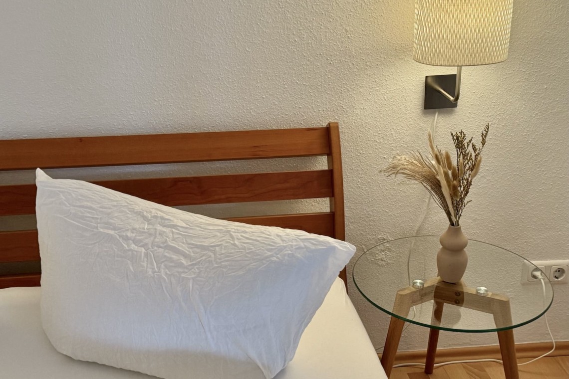 Gemütliche Ferienwohnung: Schlafzimmer mit Holzbett, Nachttischlampe und entspannter Atmosphäre. Ideal für Urlaub.