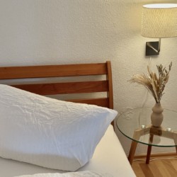 Gemütliche Ferienwohnung: Schlafzimmer mit Holzbett, Nachttischlampe und entspannter Atmosphäre. Ideal für Urlaub.